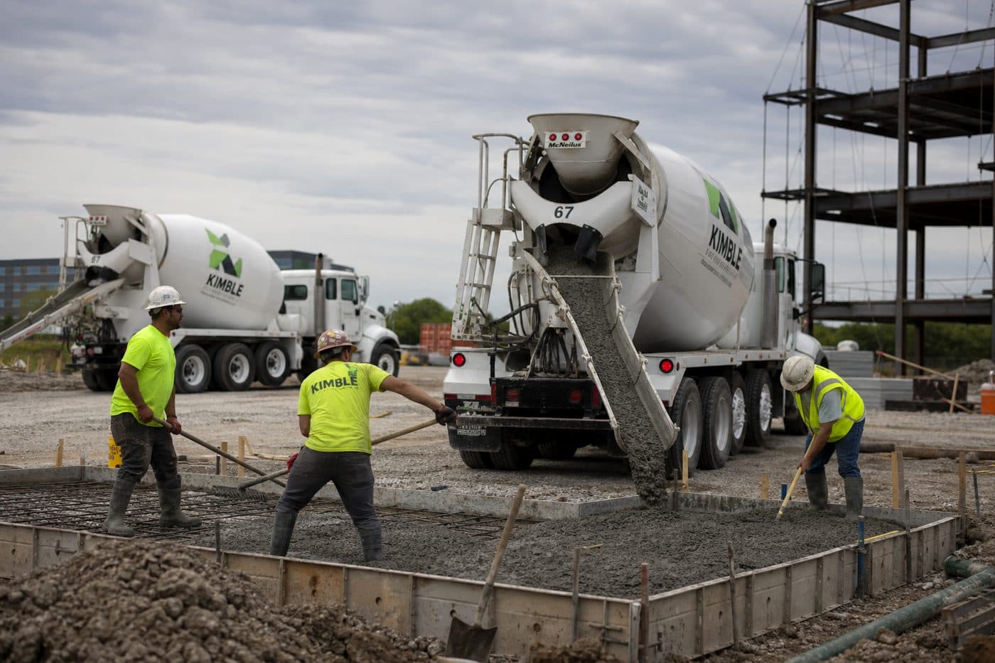 Concrete mixer trucks unloading at an active construction site, editorial context image