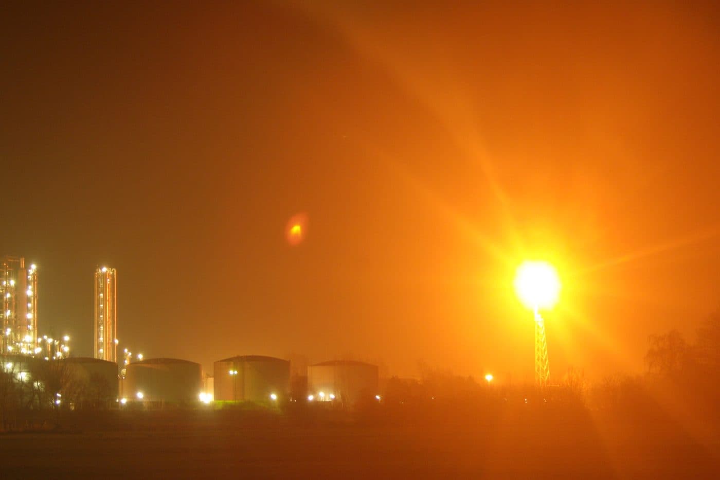 Oil refinery flare stack burning at night, editorial context image